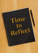 Time to Reflect on black journal notepad with pen on desk