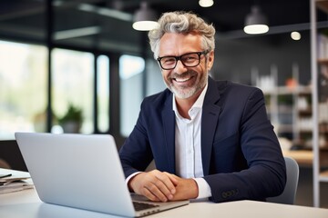 Confident and successful Caucasian businessman with a beard working at a laptop in a modern office.