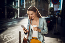 Attractive young woman walking in the city and using a smartphone