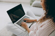 © ViDi Studio - Cropped young IT woman wearing casual clothes sits on grey sofa couch hold use work on blank screen laptop pc computer stay at home hotel flat rest relax spend free spare time in living room indoor.
