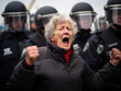 An elderly woman runs down the street screaming amidst smoke and police officers during the riots