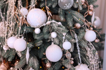 Wall Mural - Close up of beautiful fir branches with shiny golden, silver and white baubles or balls, xmas ornaments and garland lights,Christmas holidays background. Decoration on xmas tree.Festive new 2024 year.