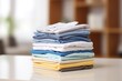 © MDBaki - Stack of clean clothes on table in room.