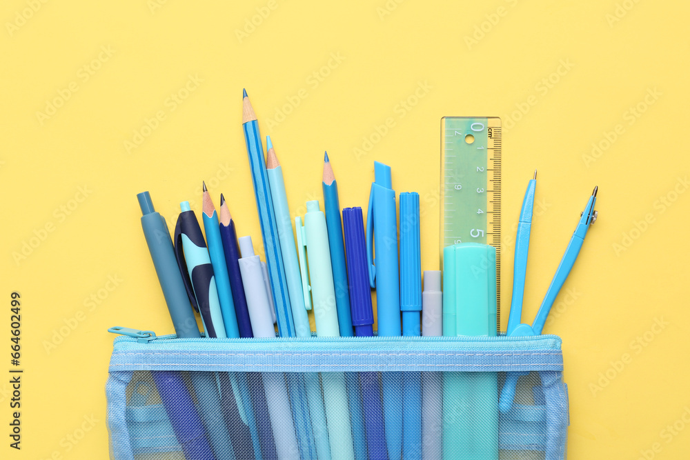 Blue pencil case with school stationery on beige background