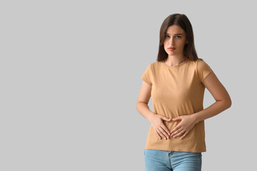 Young woman suffering from stomach ache on light background