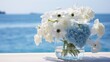 a serene arrangement of blue hydrangeas and white anemones, set against a backdrop of calm, azure waters.