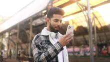 Portrait of young handsome stylish man hold smartphone scrolling social media texting browsing online at urban city Attractive guy relax enjoying great day and looking at screen at street outdoors