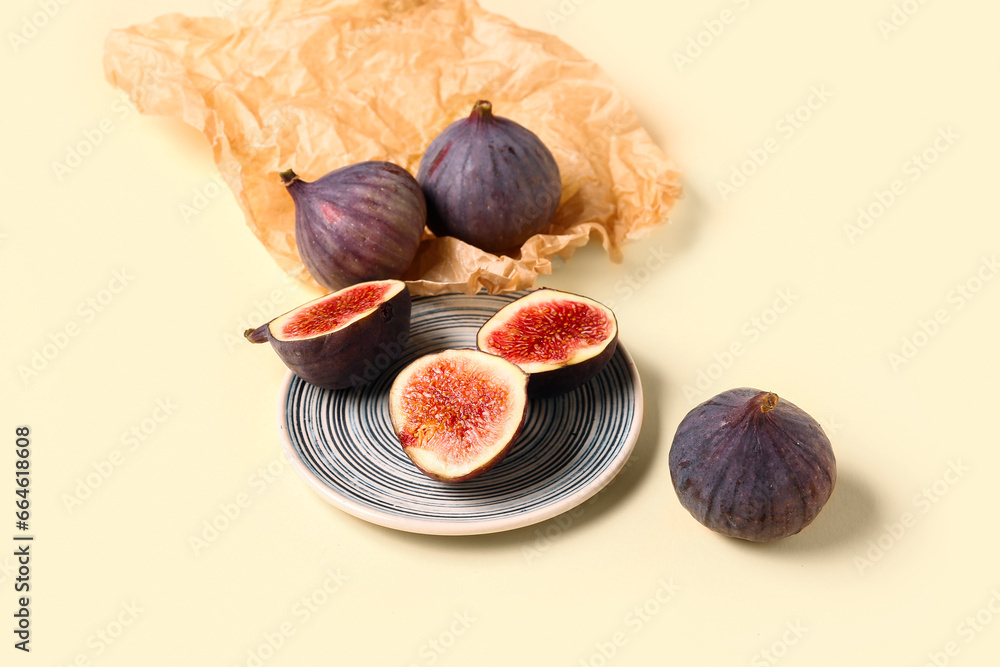 Plate with halves of fresh ripe figs on yellow background