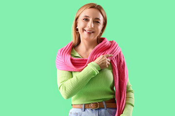 Poster - Stylish mature woman with scarf on green background