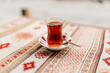 Turkish black tea in national dishes stands on the table with a napkin with Turkish patterns. Dessert close-up. Breakfast in a cafe. Turkish ornament