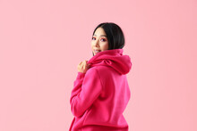 Young Asian Woman In Hoodie On Pink Background