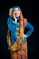 Wall Mural - Muslim woman wearing traditional wear blue kebaya and hijab isolated on blue background. Idul Fitri and hijab fashion concept.