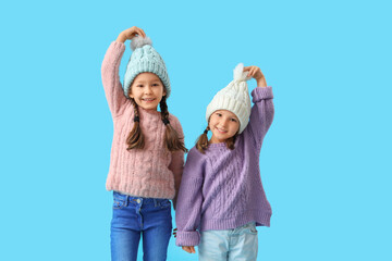 Wall Mural - Cute little girls in warm clothes on blue background