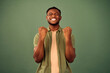 Emotion of joy. Euphoric millennial guy with closed eyes making eyes gesture while feeling frank happiness over green background. African american young man celebrating success and luck in studio.