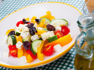 Fresh colorful Greek salad (horiatiki salad) served with feta cheese on white plate..