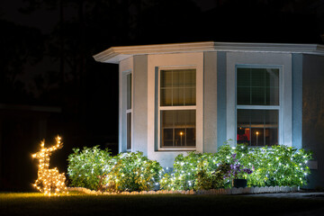 Brightly illuminated Christmas decorations on front yard of Florida family home. Outside decor for winter holidays