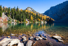 Picturesque View On Blue Lake. Autumn Mountains Landscape With Blue Lake And Bright Orange Larches In The North Cascades National Park In Washington State, USA.