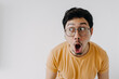 Funny asian man wow and shocked face wear yellow t-shirt isolated o n white.