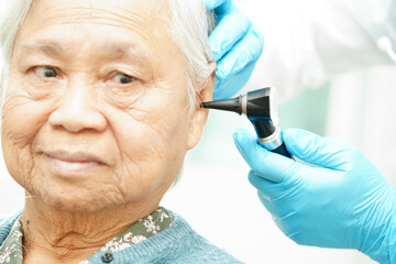 Wall Mural - Otolaryngologist or ENT physician doctor examining senior patient ear with otoscope, hearing loss problem.