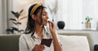 © N Felix/peopleimages.com - Home, relax and woman with chocolate bar, smile and eating with candy, hungry and dessert. Person, apartment or girl on a sofa, candy or sweet treats with a snack, nutrition or diet plan with cacao