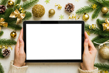 Christmas Online Shopping From Home, Female Hands Holding Tablet Pc With Blank White Display Top View. Woman Hand Holding Tablet With Blank Screen, Christmas Tree And Gifts On Background
