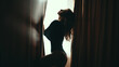 Silhouette of beautiful woman with long curly hair in black bodysuit on light window background. Lifestyle, copyspace.