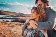 © simona - Young adult couple in love in outdoor leisure activity admiring travel destination. Contemplation. People traveler and adventure lifestyle. Man hug woman from behind. Looking away, togetherness two