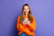 © deagreez - Photo of excited teen girl browsing brand new iphone 15 check for modern features last release device isolated on violet color background