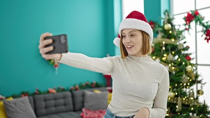 Wall Mural - Young blonde woman doing video call waving celebrating christmas at home