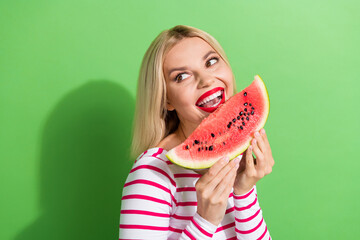 Canvas Print - Portrait of cheerful girl with short hair dressed striped clothes biting watermelon look empty space isolated on green color background