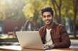 Young college student using laptop, smiling