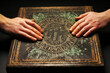 Group of hands touching Ouija board planchette, plain background.