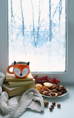 Wall Mural - Fox shape mug, books, cookies, nuts, warm sweater on windowsill. home hygge comfort in snowy cold weather, relax and reading concept. Christmas, New Year holidays background. festive winter season