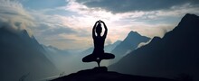 Silhouette Of A Woman Practicing Yoga In The Summit With Mountain Background.