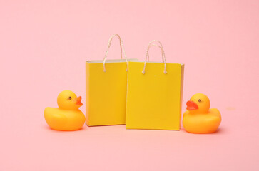 Wall Mural - Paper Miniature shopping bags with rubber ducks on a pink background. Black Friday, world shopping day, sale