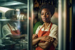 © ADDICTIVE STOCK - Generative AI illustration of black waitress in apron waiting in a restaurant kitchen while looking at the camera against a blurred background