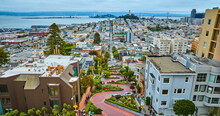 Winding Lombard Street with cars going downhill with distant Coit Tower aerial