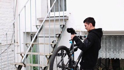 Wall Mural - A young man hangs a bicycle on a rack for repair.