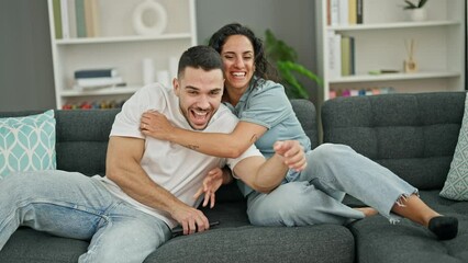 Poster - Man and woman couple hugging each other watching television at home