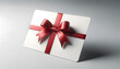 3D depiction of a blank white gift card, oriented diagonally, secured with a shimmering red ribbon tied neatly in a bow. The card stands out against a calm grey setting, casting a faint shadow
