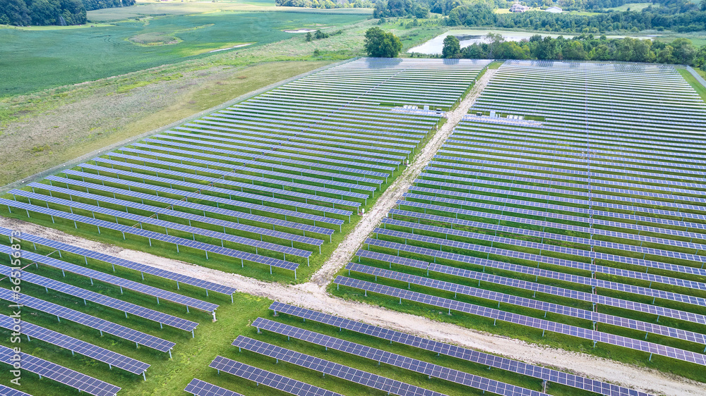 Horizontal rows of solar panels with dirt road between sections and ...