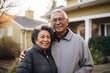 Portrait of a happy senior couple in front of their house