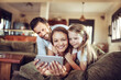 © Geber86 - Happy young family looking at the smartphone on the couch at home