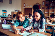 © Marko Geber - Diverse pair of children writing together at the elementary school