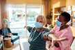 © Marko Geber - Young African American female caregiver helping her senior patient stretch at home