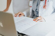© qunica.com - An experienced doctors examines an elderly patient, discussing and analyzing medical results.