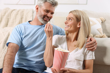 Wall Mural - Happy affectionate couple with popcorn spending time together at home. Romantic date