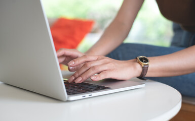 Wall Mural - Casual business woman hand typing on laptop computer on table, online working, surfing the internet. Female freelancer working in coffee shop or home office, close up, freelance lifestyle concept