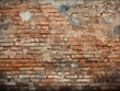 A worn-out brick wall with evident signs of wear and patches of old plaster. Some bricks have chipped corners, and there are occasional elements like metal and patches of paint.