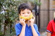 © Austockphoto - Happy primary school student holding a banana up to his face